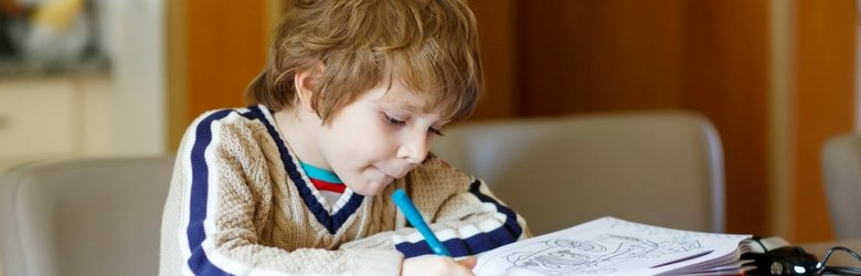 young boy using his colouring in book with his blue pen