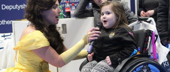 little girl in wheelchair singing through microphone