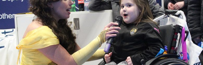 little girl in wheelchair singing through microphone