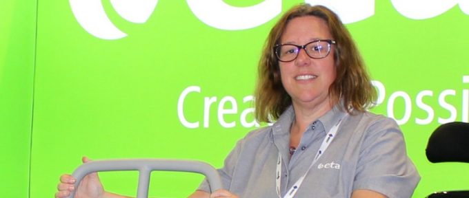 Jo stood at etac exhibition stand holding onto equipment