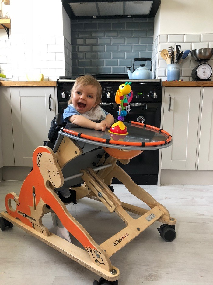 baby smiling in wooden high chair