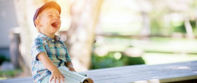 young boy smiling holding a book